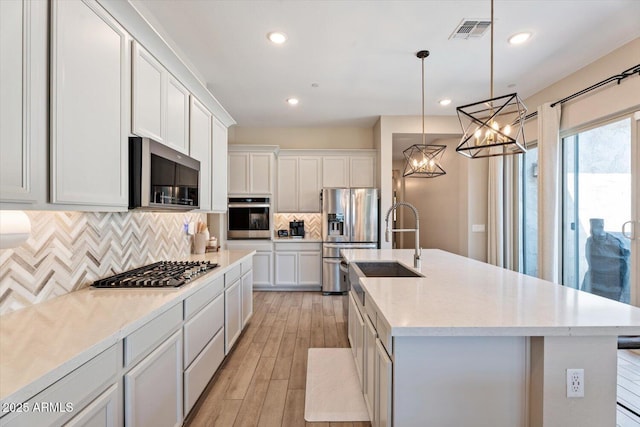 1895 N 141st Ave, Goodyear, AZ 85395 - kitchen with appliances with stainless steel finishes, a chandelier, a sink, an island with sink, and decorative backsplash