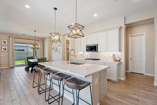 1895 N 141st Ave, Goodyear, AZ 85395 - kitchen featuring stainless steel microwave, a sink, gas stovetop, light wood-style flooring, and tasteful backsplash