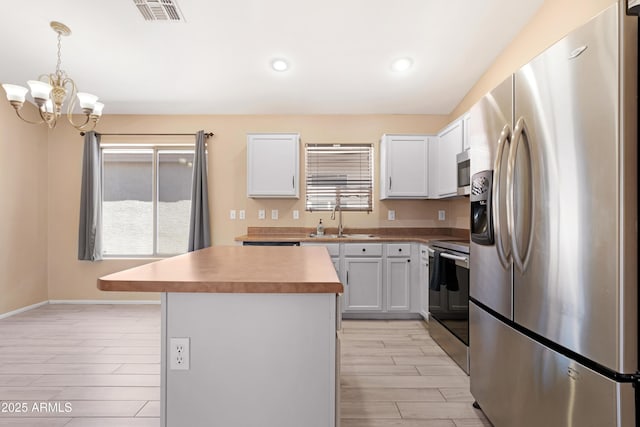 kitchen with visible vents, wood finish floors, a sink, a chandelier, and stainless steel appliances