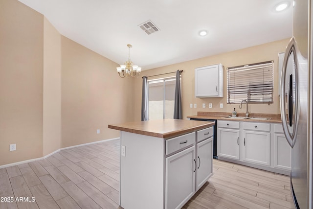 kitchen featuring light wood-type flooring, freestanding refrigerator, white cabinets, and a chandelier