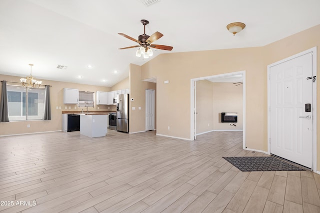 unfurnished living room featuring baseboards, light wood-type flooring, lofted ceiling, and ceiling fan with notable chandelier