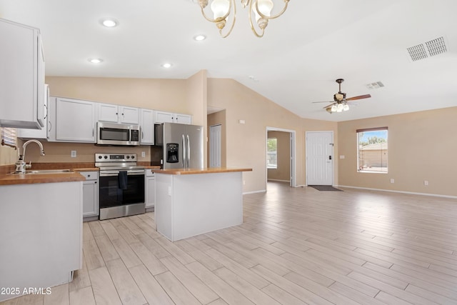 kitchen with appliances with stainless steel finishes, a sink, open floor plan, lofted ceiling, and visible vents