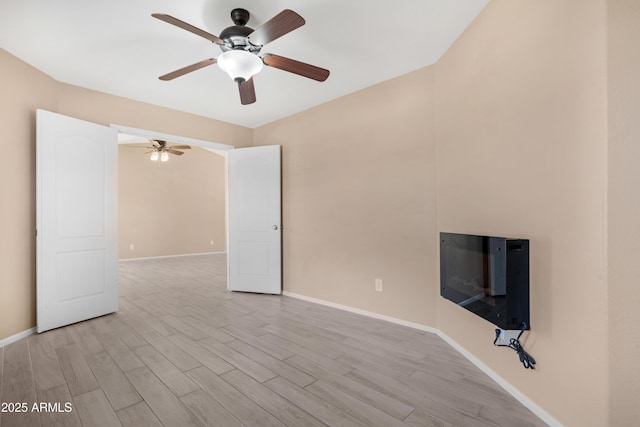 unfurnished living room with a ceiling fan, baseboards, and light wood-style flooring