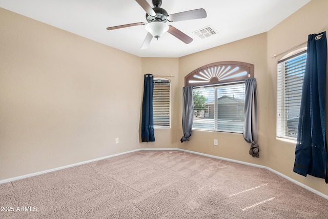 unfurnished room featuring a wealth of natural light, ceiling fan, carpet, and visible vents