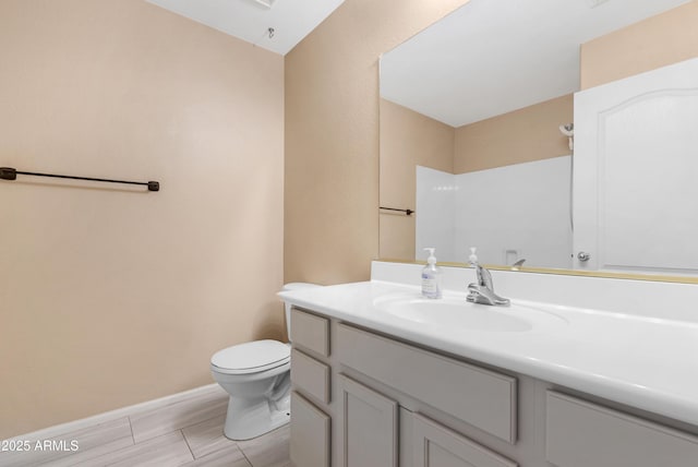 bathroom featuring toilet, baseboards, and vanity