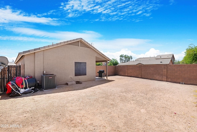 rear view of house featuring a patio, central AC unit, a fenced backyard, and stucco siding