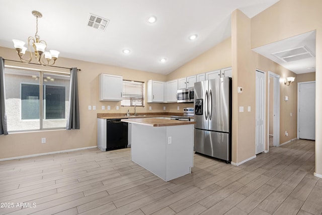 kitchen featuring white cabinets, light wood finished floors, a center island, stainless steel appliances, and visible vents