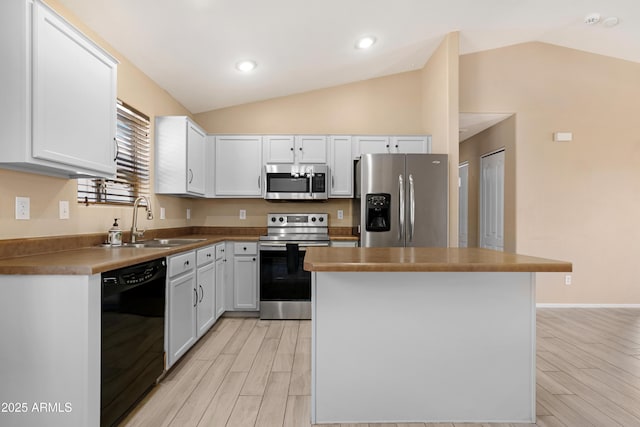 kitchen with stainless steel appliances, vaulted ceiling, a sink, and light wood finished floors