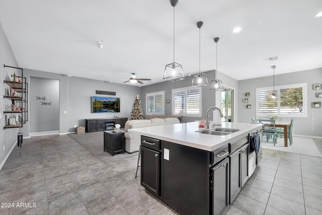 kitchen with ceiling fan, sink, decorative light fixtures, a center island with sink, and a breakfast bar area