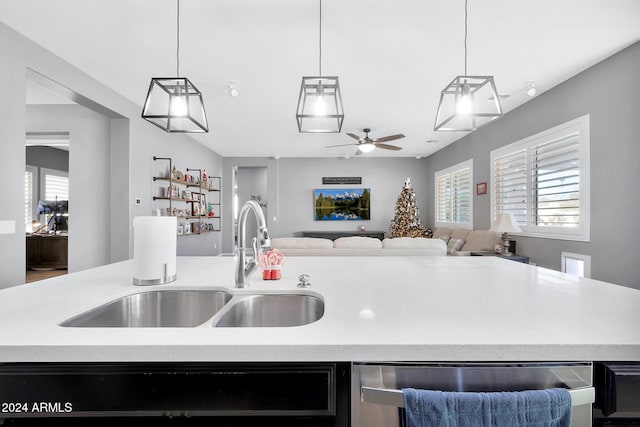 kitchen featuring stainless steel dishwasher, ceiling fan, sink, hanging light fixtures, and an island with sink