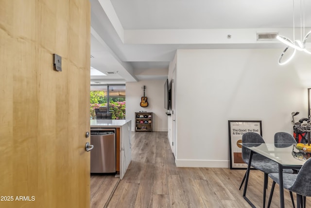 kitchen with baseboards, visible vents, light wood-style flooring, light countertops, and stainless steel dishwasher