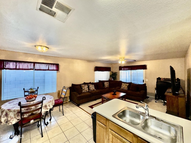 kitchen featuring visible vents, open floor plan, light countertops, light tile patterned flooring, and a sink