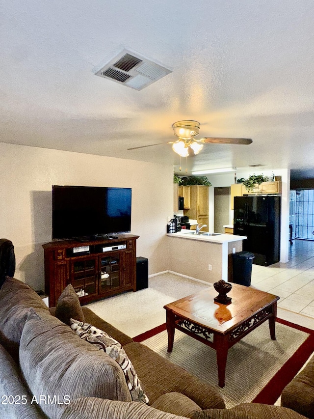 living area with visible vents, a textured ceiling, and a ceiling fan