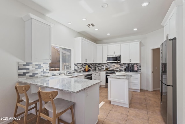 7736 W Tumblewood Dr, Peoria, AZ 85382 - kitchen featuring appliances with stainless steel finishes, a peninsula, tasteful backsplash, white cabinetry, and light stone countertops