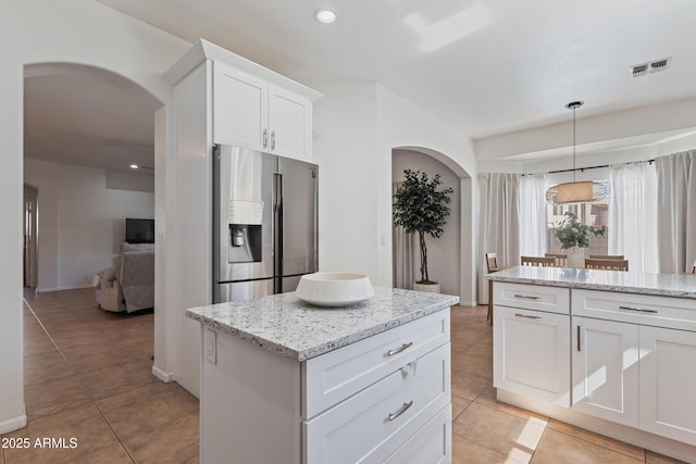 7736 W Tumblewood Dr, Peoria, AZ 85382 - kitchen featuring stainless steel fridge with ice dispenser, arched walkways, white cabinetry, light tile patterned floors, and light stone countertops