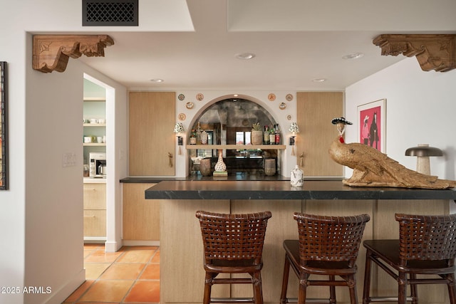 bar with light brown cabinetry and light tile patterned floors