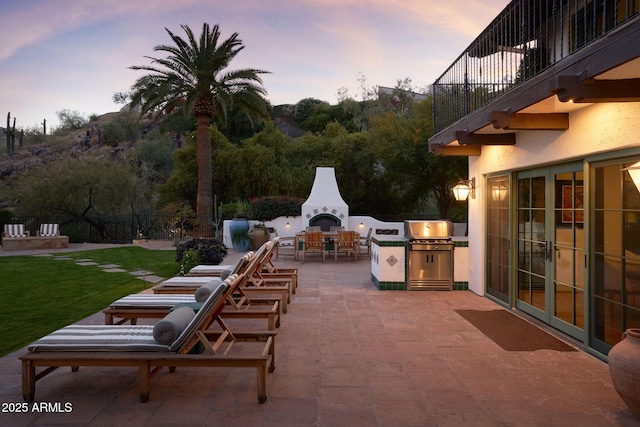 patio terrace at dusk featuring exterior fireplace