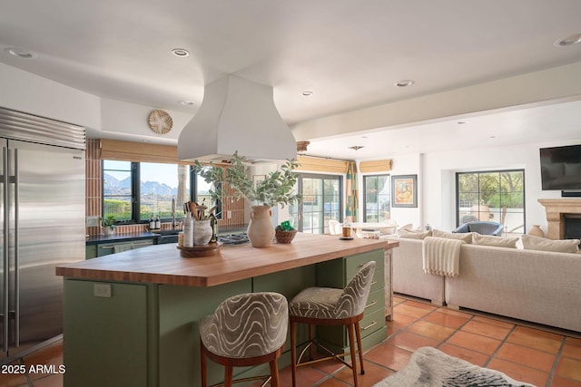 kitchen with a healthy amount of sunlight, stainless steel appliances, a mountain view, a kitchen bar, and butcher block countertops