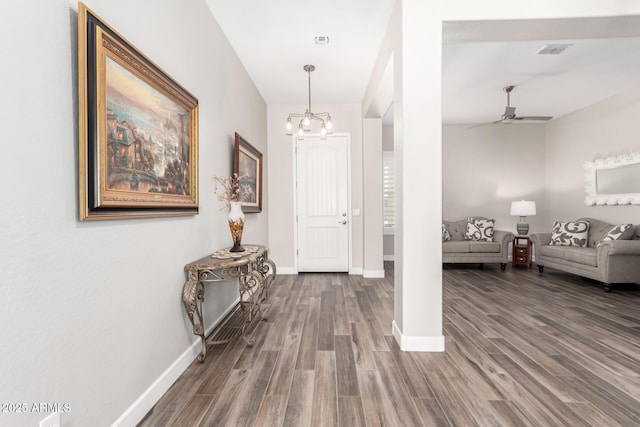 foyer entrance featuring ceiling fan with notable chandelier, visible vents, baseboards, and wood finished floors