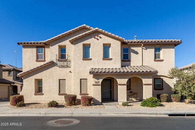 mediterranean / spanish-style home with a porch, a tile roof, and stucco siding