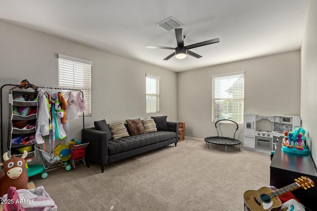 living room with carpet floors, visible vents, and a ceiling fan