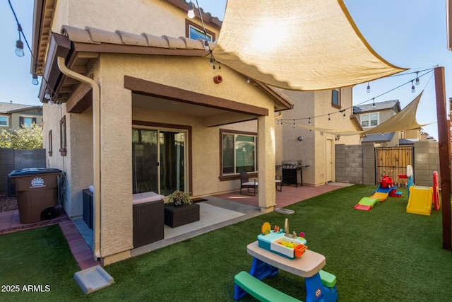 rear view of house featuring fence private yard, a lawn, a playground, and stucco siding