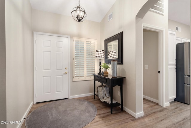 entryway with an inviting chandelier and light hardwood / wood-style flooring