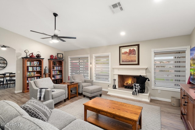 living room featuring ceiling fan, vaulted ceiling, and light hardwood / wood-style floors