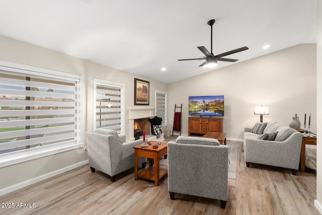 living room featuring ceiling fan, light hardwood / wood-style flooring, and lofted ceiling