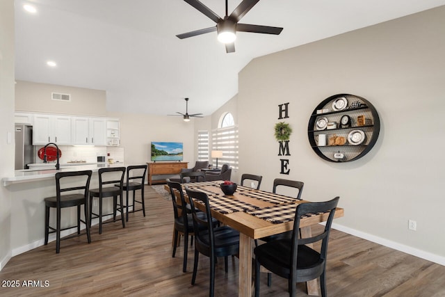 dining room featuring dark wood-type flooring, vaulted ceiling, and ceiling fan