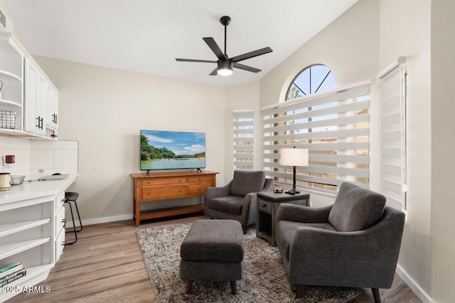 living area featuring light hardwood / wood-style floors, ceiling fan, and vaulted ceiling