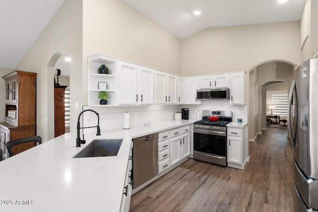 kitchen with white cabinets, appliances with stainless steel finishes, tasteful backsplash, sink, and high vaulted ceiling