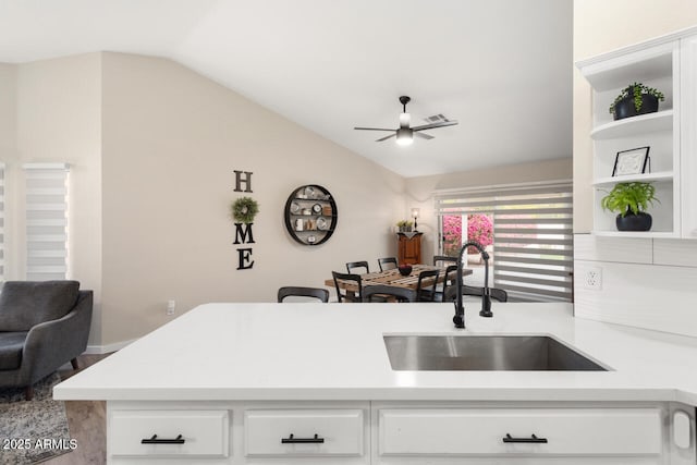 kitchen with white cabinets, sink, kitchen peninsula, vaulted ceiling, and ceiling fan