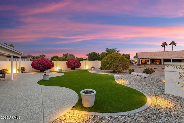 yard at dusk featuring a patio