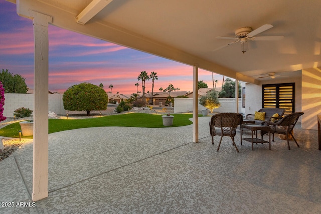 patio terrace at dusk featuring ceiling fan and a lawn