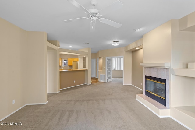 unfurnished living room featuring ceiling fan, light colored carpet, visible vents, baseboards, and a tiled fireplace