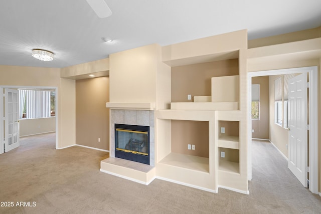 unfurnished living room featuring carpet floors, a fireplace, baseboards, and a wealth of natural light