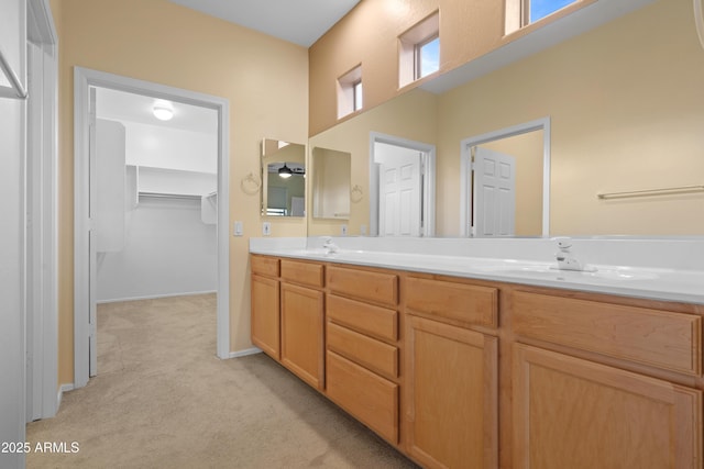 full bath featuring carpet floors, a walk in closet, double vanity, a sink, and baseboards