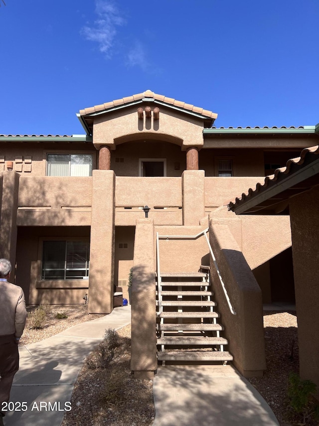 entrance to property with a tile roof and stucco siding