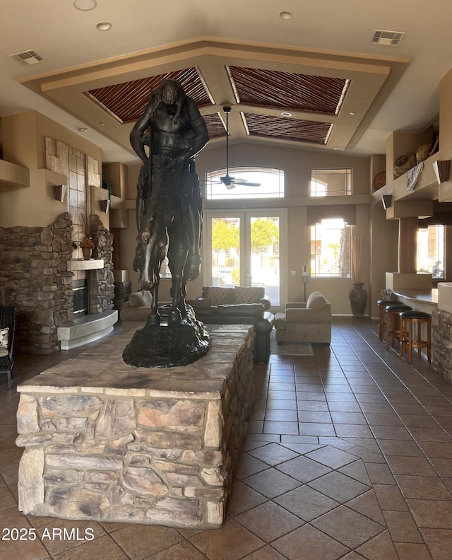 living room featuring a stone fireplace and visible vents