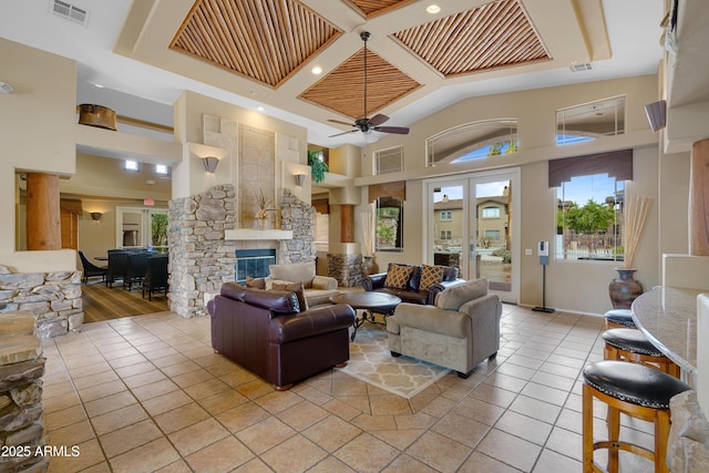 living room with visible vents, a stone fireplace, a towering ceiling, and light tile patterned floors