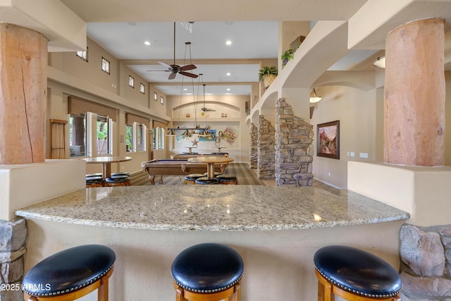 kitchen with arched walkways, stone counters, recessed lighting, a ceiling fan, and ornate columns