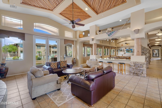 living room featuring ceiling fan, high vaulted ceiling, light tile patterned floors, arched walkways, and decorative columns