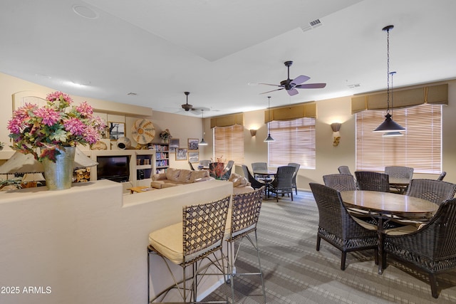 kitchen with a ceiling fan, visible vents, carpet flooring, and decorative light fixtures