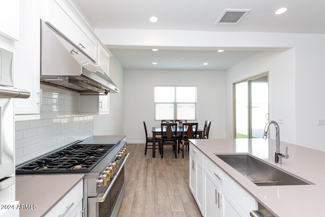 kitchen featuring white cabinetry, sink, high end stainless steel range oven, and light wood-type flooring