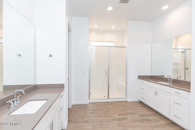 bathroom with vanity, hardwood / wood-style flooring, and a shower with door