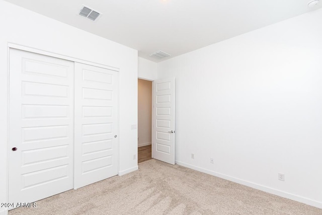 unfurnished bedroom with light carpet and a closet