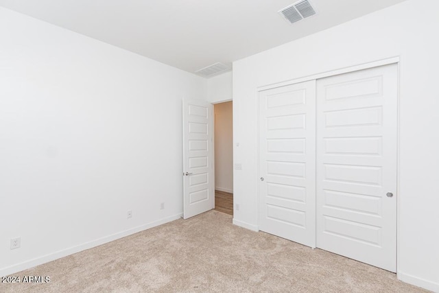 unfurnished bedroom with light carpet and a closet