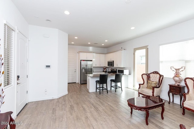 kitchen with a center island, white cabinets, a kitchen breakfast bar, appliances with stainless steel finishes, and light hardwood / wood-style floors