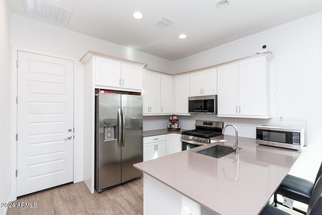 kitchen featuring white cabinets, appliances with stainless steel finishes, light hardwood / wood-style flooring, and sink